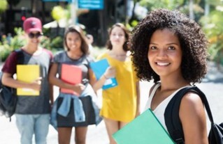One girl smiling in the foreground with three other students smiling in the background.